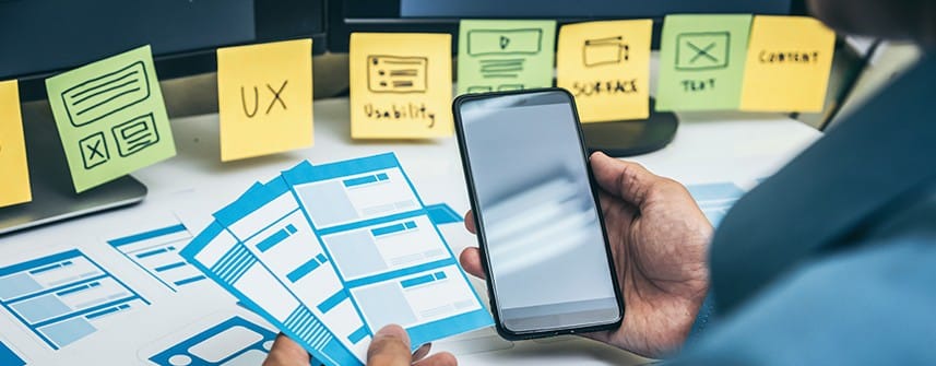 Importance of User Experience (UX) in Custom Web Application Development 1 Person holding mobile with sticky notes shows UX in web application development